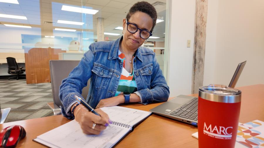 Person writing on planner with a laptop and MARC water container