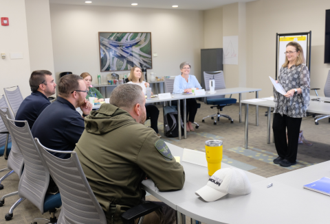 Group of people seated around a room listening to the instructor